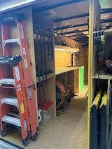 the inside of a garage with tools and equipment stored in storage compartments, including ladders