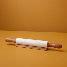 a rolling pin on a yellow surface with a wooden handle