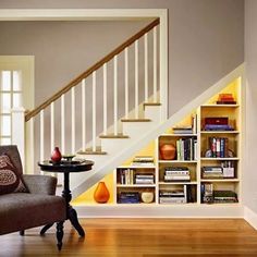 a living room filled with furniture and a book shelf next to a stair case full of books