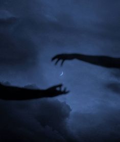 two hands reaching towards each other in front of a cloudy sky with the moon behind them