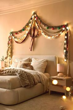 a bedroom decorated for christmas with lights on the headboard and garlands hanging over the bed