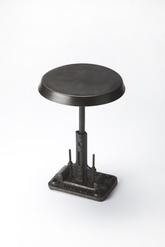 a round table with metal legs and a black top on a white surface, against a plain background