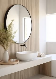 a white bowl sitting on top of a counter next to a mirror and bathtub