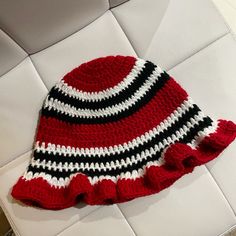 a red and black knitted hat sitting on top of a white couch