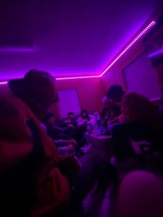 a group of people sitting in a room with purple lighting