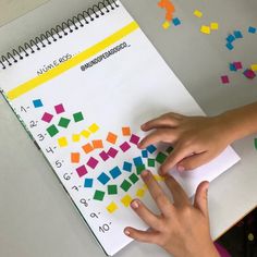 a child's hand on top of a notebook with colored stickers