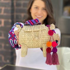 Elevate your fashion game with this playful and charming pig-shaped hand-woven raffia handbag from Oaxaca, Mexico. This bohemian straw bag with its unique design is perfect for anyone looking for a standout accessory. Complete with a hand-woven strap and a matching tassel, this bag captures the authentic craftsmanship and vibrant spirit of Mexican artistry. Whether you're in the market for fun handbags or simply adore bohemian straw bags, this piece is a delightful and expressive addition to your collection. Embrace the artistic tradition of hand-woven straw while showcasing your free-spirited style with this boho-chic raffia handbag.Pompons may vary but will match the color of the strap . Dimensions:Length: 12-11 inches.Height: 9-7 inches.Strap: 34-36 inches length. 17 inches drop approx. Pig Handbags, Wool Knit Scarf, Handcrafted Boots, Painted Hats, Free Spirit Style, Cashmere Shawl, Straw Bags, Shoulder Backpack, Woven Raffia