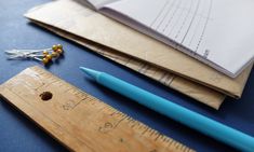 rulers, pencils and pins are sitting next to each other on a blue surface