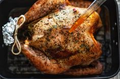 a roasting turkey with herbs and seasonings in a roaster pan, ready to be cooked