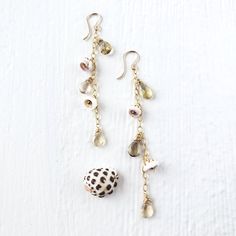 It's time to get away from the everyday world and get immersed in the true beauty of nature with these fun and playful 14kt—gold-filled, dangle earrings. Inspired by the beautiful waterfalls of Hawaii, with puka shells with natural gems, enjoy the unique colors; these lightweight and comfortable are a perfect accessory for any occasion. Choose from rainbow moonstone, London blue topaz, natural Italian red coral, pink tourmaline, whiskey quartz, or Labradorite. 3.5"L. Due to the handmade nature, Natural Color Dangle Jewelry For Beach, Natural Dangle Jewelry For Beach, Natural Dangle Beach Jewelry, Beach Jewelry With Dangling Charms, Natural Color Dangle Jewelry For Gifts, Nature-inspired Natural Color Dangle Jewelry, Natural Color Drop Earrings For Vacation, Nature-inspired Jewelry With Dangling Beads For Gifts, Nature-inspired Dangle Jewelry In Natural Color