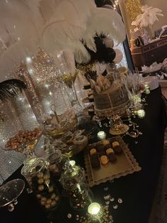 a black table topped with lots of desserts and cake covered in white feather decorations