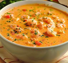 a bowl of soup with shrimp and garnishes on the top, ready to be eaten