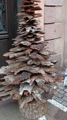 a tree made out of logs sitting on the side of a building in front of a door