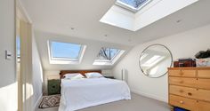 an attic bedroom with two skylights and a bed in the corner, along with a dresser