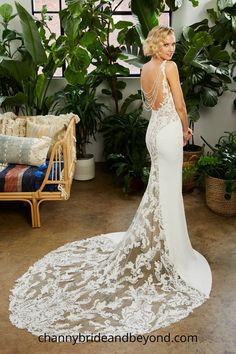 a woman in a white wedding dress standing next to a couch and potted plants