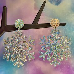 the snowflake earrings are hanging from a pair of black hair clippers on a purple and blue background