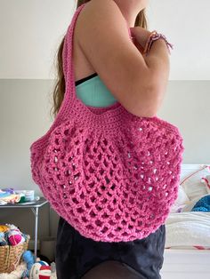 a woman is holding a pink crocheted bag