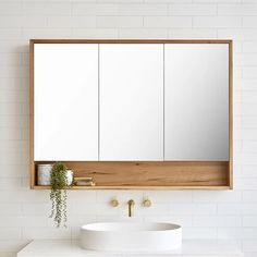 a white sink sitting under a bathroom mirror next to a wall mounted faucet