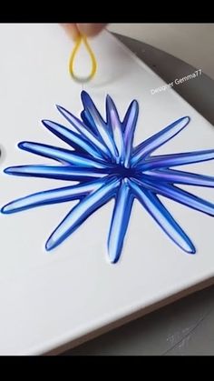 a person is cutting something with scissors on a white board that has blue glass flowers