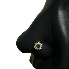 a close up view of a nose with an emerald and white diamond ring on it