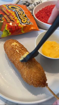 a person holding a toothbrush in front of a plate with food on it and a bag of chips to the side