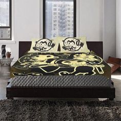 a bed with black and yellow comforters in a bedroom next to a large window