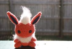 a crocheted stuffed animal sitting on top of a table next to a fence