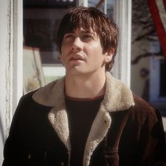 a young man standing in front of a store with his eyes closed and looking off to the side