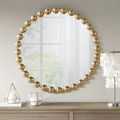 a large round mirror sitting on top of a dresser next to a vase and lamp