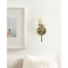 a candle is lit on the wall next to a white pillow and framed photograph in a living room