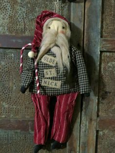 an old fashioned doll hanging on the wall with a red and black suit underneath it