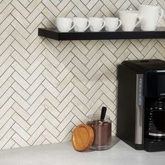 a coffee maker sitting on top of a counter next to cups