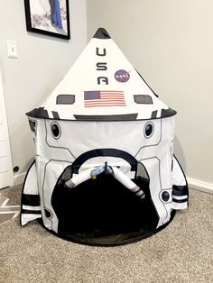 an inflatable space shuttle sits on the floor next to a framed photo and wall