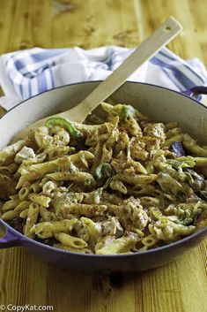 a pan filled with pasta and vegetables on top of a wooden table