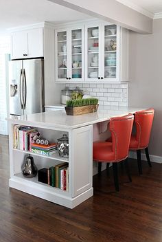 a kitchen with white cabinets and red chairs