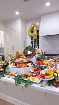 a table filled with lots of food on top of a kitchen counter next to white cabinets