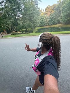 a woman with headphones is walking down the street while holding her hand out in front of her