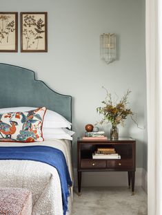 a bedroom with a bed, nightstand and paintings on the wall