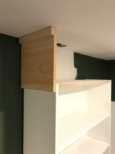 an unfinished shelf in the corner of a room with green walls and white shelving