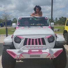 a woman is sitting on the hood of a white jeep with pink trim and accessories