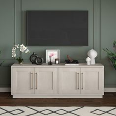 a living room with green walls and a tv on the wall, surrounded by potted plants