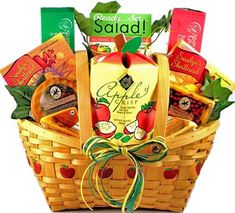 a basket filled with fruit and snacks sitting on top of leaves next to an orange pumpkin