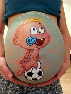 a pregnant woman holding a soccer ball painted on her belly with the image of a cartoon character