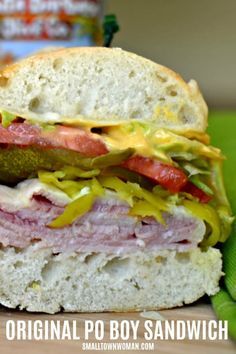 a close up of a sandwich with meat and vegetables on it next to a can of soda