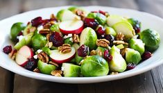 brussel sprouts with apples, cranberries and pecans in a white bowl