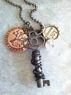 an old key is attached to a chain with two charms and a coin on it