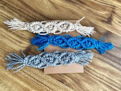 three crocheted bracelets are sitting on a wooden surface, one is blue and the other is white