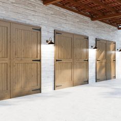 three wooden garage doors in front of a white brick wall with lights on each side