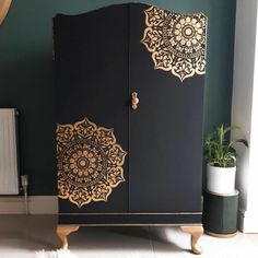 a black and gold armoire next to a potted plant in a room with green walls