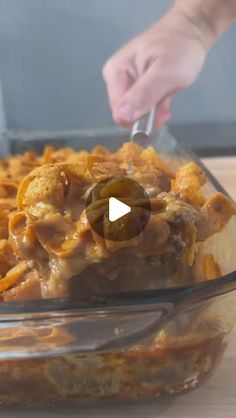 a glass casserole dish filled with pasta and cheese being spooned into it